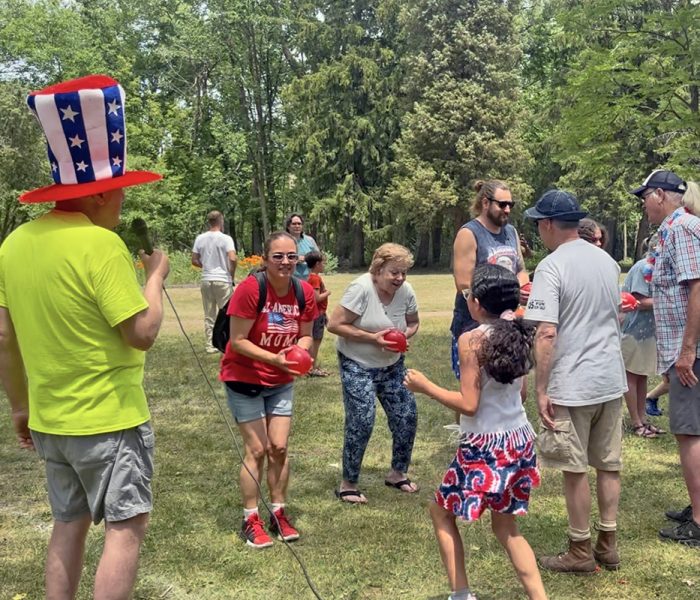 Izaak Walton Membership Secretary Shawn Straney, left in the top hat, leads a game of water balloon toss at the community picnic. (Nick Ulanowski/ H-F Chronicle)
