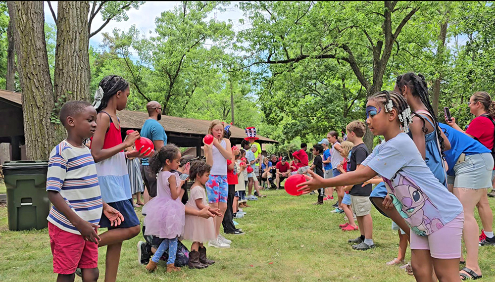 Jamin Hampton, left, and Myracle Dunning are partners in one of the balloon toss games during the Izaak Walton community picnic on the 4th of July. (Eric Crump/H-F Chronicle)