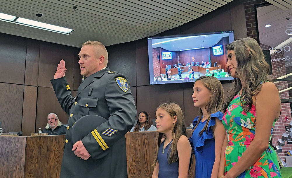 Douglas Merkle takes the oath of office at the July 21 Flossmoor board meeting to become the village's deputy police chief while his family looks on. He succeeds Keith Taylor, who served in the position since August 2022. (Eric Crump/H-F Chronicle)