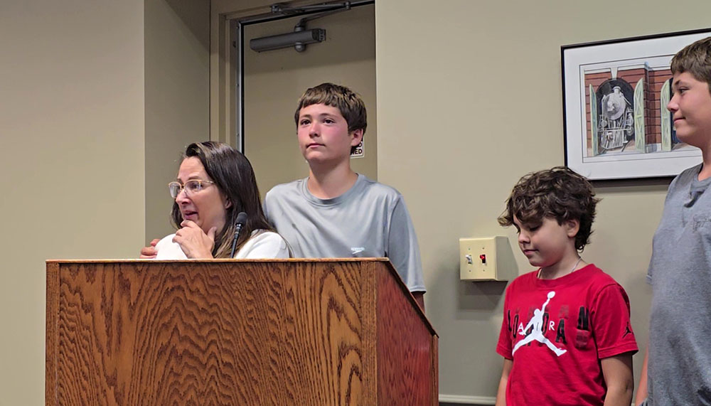 Maggie Gosselin, left, with her two sons and their friend, tells the Homewood board that her sons were outside and heard shots fired nearby on July 21. (Eric Crump/H-F Chronicle)