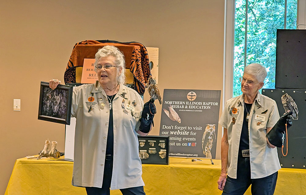 Candy Ridlbauer and her assistant, Cathy Hoover, show visitors screech owls at the Birds of Prey presentation at Irons Oaks. (Chris Weber/H-F Chronicle)