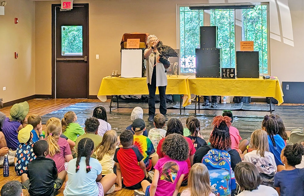 Candy Ridlbauer and Athena the great-horned owl tell kids at Irons Oak about raptors. (Chris Weber/H-F Chronicle)