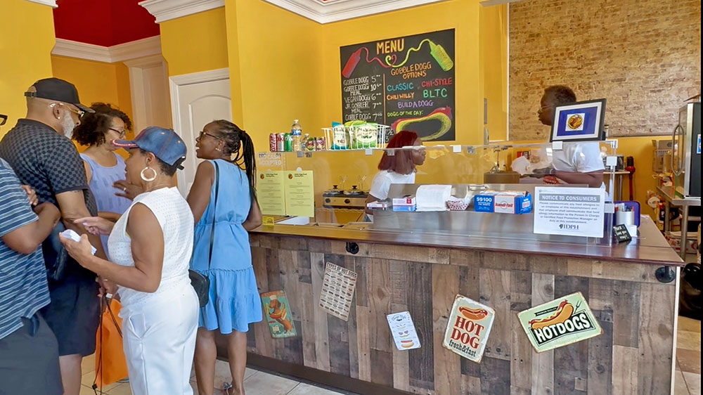 Attendees at the Gobble Doggs grand opening in Homewood wait in line for their complimentary hot dog samples. (Summer Kiswani/ H-F Chronicle)