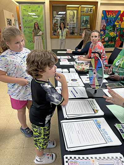 Churchill School student Grace Sailbery and her brother Ryker, a student at Willow School, prepare to spin the wheel to win a prize. The game was at an information table during Churchill School's open house. (Marilyn Thomas/H-F Chronicle)