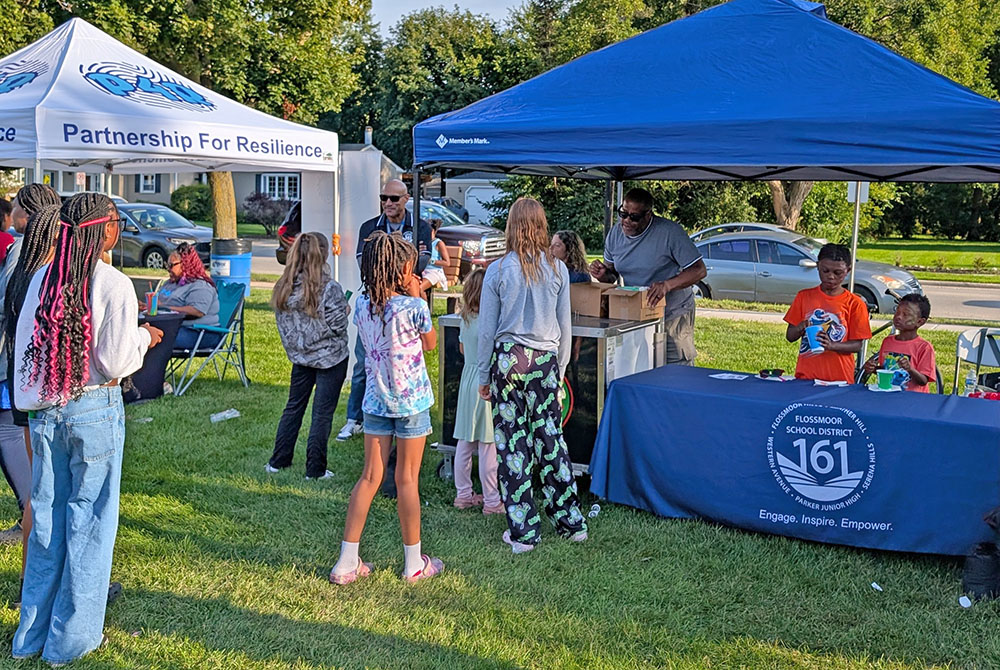 Superintendent Dana Smith and District 161 Board Member Theartris Childress III hand out frozen treats to a line of students. (Chris Weber/H-F Chronicle)
