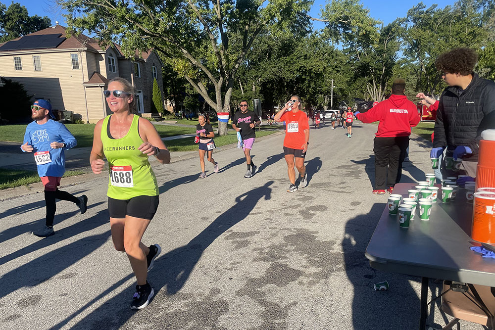 Runners pass the Flossmoor Hills water station during the 2025 Hidden Gem Half Marathon. (Jamilah Lewis/H-F Chronicle)