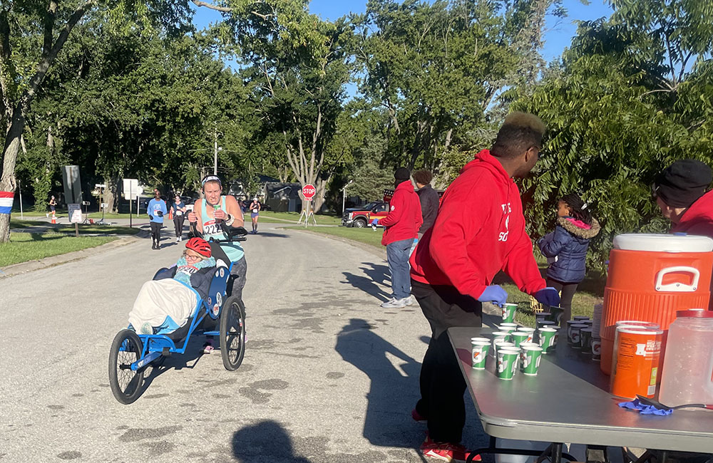 A runner who's helping another participant stops for water in Flossmoor Hills. (Jamilah Lewis/H-F Chronicle)