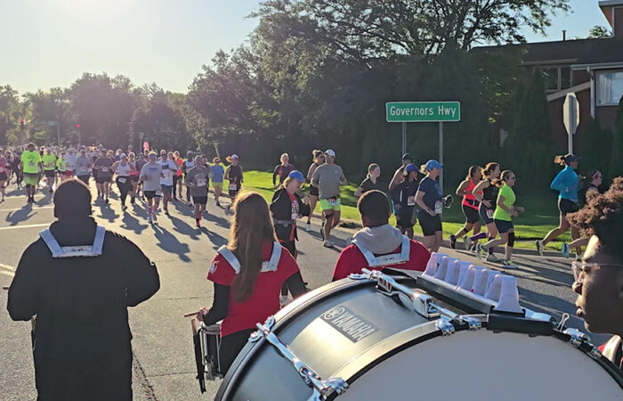 Runners get an early boost of energy from Homewood-Flossmoor High School Marching Band percussionists as they make the first turn in the race from Flossmoor Road onto Baythorne Drive. (Eric Crump/H-F Chronicle)