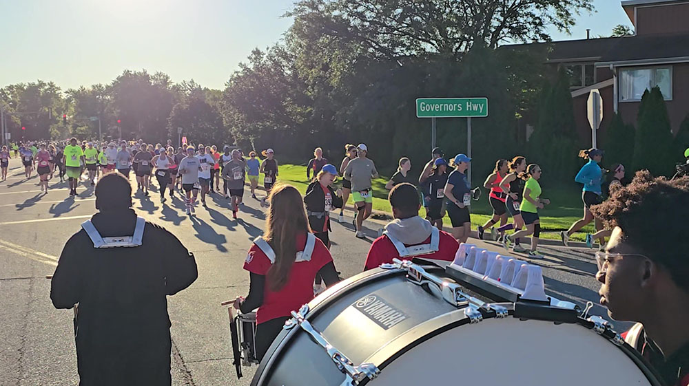 Runners get an early boost of energy from Homewood-Flossmoor High School Marching Band percussionists as they make the first turn in the race from Flossmoor Road onto Baythorne Drive. (Eric Crump/H-F Chronicle)