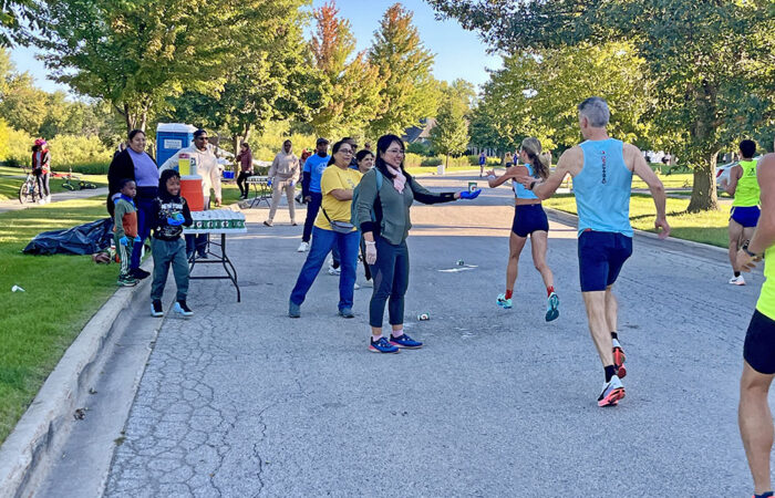 Bansari Modi, Yule Yeh, and 7-year-old Roman Ford hand out Gatorade to runners during the Hidden Gem Half Marathon in Flossmoor. (Nuha Abdessalam/H-F Chronicle)