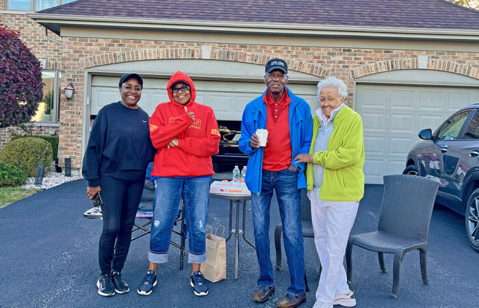 Debora Matthews joins Hetti Collins, along with James and Jeanne Wilder, outside Collins’ home to cheer on runners during the Hidden Gem Half Marathon in Flossmoor. (Nuha Abdessalam/H-F Chronicle)