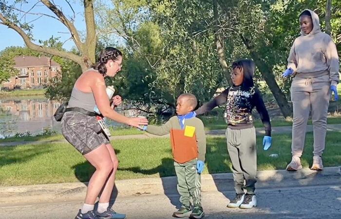 A runner grabs Gatorade from 4-year-old Malachi Ford as his brother, Roman, and mother, Karen, cheer during the Hidden Gem Half Marathon in Flossmoor. (Nuha Abdessalam/H-F Chronicle)