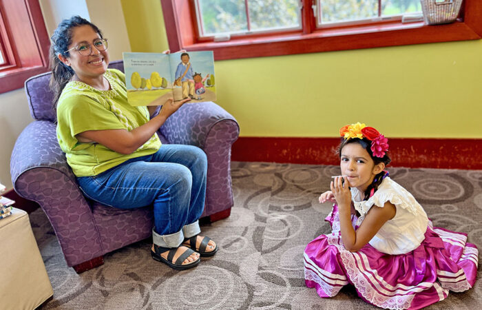 Elena, 6, joins Jessica Cheney for a bilingual story at the library’s first Hispanic Heritage Month event. (Nuha Abdessalam/H-F Chronicle)
