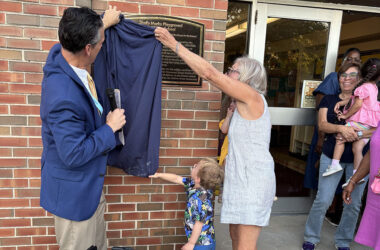 District 153 superintendent Scott McAlister helps Shelly Marks pull down the blue drape that unveils a plaque announcing the dedication of the playground at Willow School honoring her 32 years on the school board. (Marilyn Thomas/H-F Chronicle)