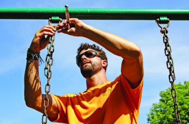 Gabe Gacsko, certified playground inspector at the Homewood-Flossmoor Park District, tightens a swing set at Irwin Park in Homewood. (Hailey Hoffman photos/H-F Chronicle)