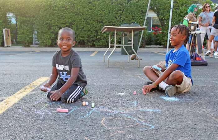 Creating their own fun. Brothers Roman and Malachi Ford take a break from the festival buzz for some chalk drawing. (Nuha Abdessalam/H-F Chronicle)