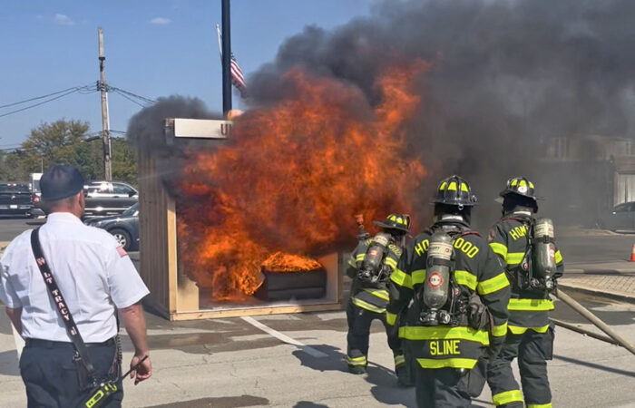 Homewood firefighters set two rooms on fire, one protected with a sprinkler system and the other not, as a part of an annual fire safety display at the Homewood Fire Department open house. Homewood Fire Lieutenant Ryan Tracy looks on. (Nick Ulanowski/H-F Chronicle)
