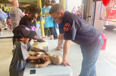 Flossmoor resident Karla Hughes learns the basics of CPR with her 7-year-old nephew, Aayyan Hughes, from Homewood firefighter and EMT Ryan Hope. (Nick Ulanowski / H-F Chronicle)