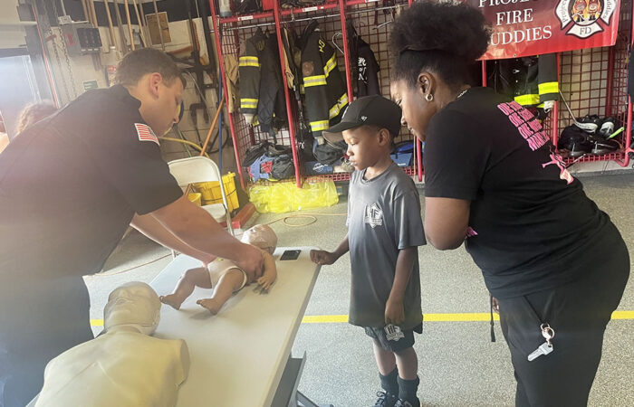 Flossmoor resident Karla Hughes learns the basics of CPR with her 7-year-old nephew, Aayyan Hughes, from Homewood firefighter and EMT Ryan Hope. (Nick Ulanowski / H-F Chronicle)