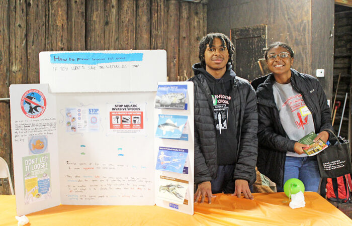 H-F High students Kanema Johnson and Nazir Rhea beside a poster on how to stop invasive aquatic species. (Nuha Abdessalam/H-F Chroniocle)