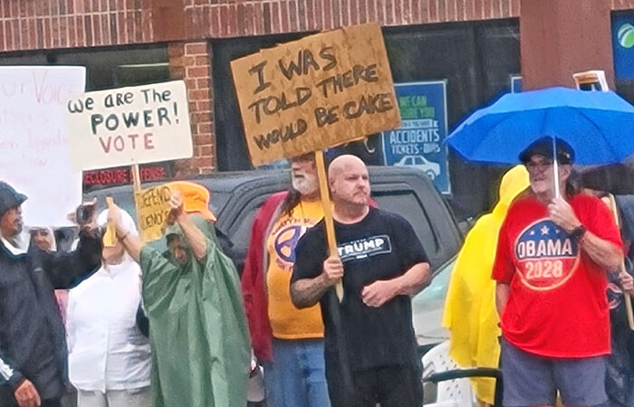A man wearing a Trump shirt and holding a sign that reads, "I was told there would be cake," stands next to a man wearing an "Obama 2028" shirt. The apparent Trump supporter was one of at least two who attended the otherwise anti-Trump rally in the Beverly neighborhood on Oct. 18. (Eric Crump/H-F Chronicle)