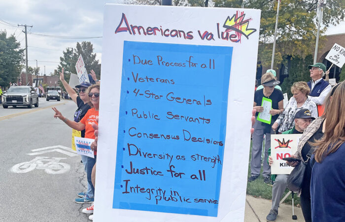 A protester shows a sign that lists American values including "due process for all," "justice for all" and "integrity in public service" at the No Kings protest Oct. 18 in Homewood. (Jamilah Lewis/H-F Chronicle)