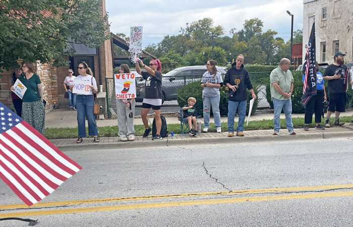 Protesters stand on the sidewalk along Harwood Avenue with signs saying "No Kings" and "Veto Cheeto," referring to a derogatory nickname for President Donald Trump, at the No Kings protests Oct. 18 In Homewood. (Jamilah Lewis/H-F Chronicle)