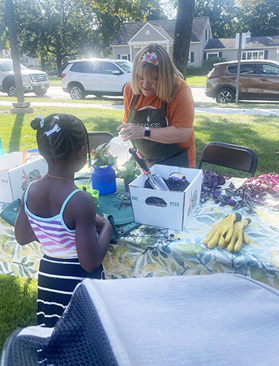 Kris McManus of Gather & Moss puts together a potted plant for a child at OAKtoberfest in Flossmoor on Oct. 4. (Jamilah Lewis/H-F C'hronicle)
