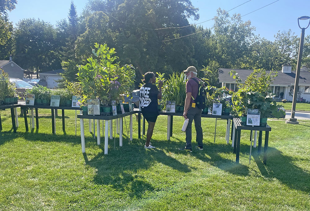 Flossmoor Green Commission Chair Tristan Shaw talks with a resident about plants for sale at OAKtoberfest in Flossmoor on Oct. 4. (Jamilah Lewis/H-F Chronicle)
