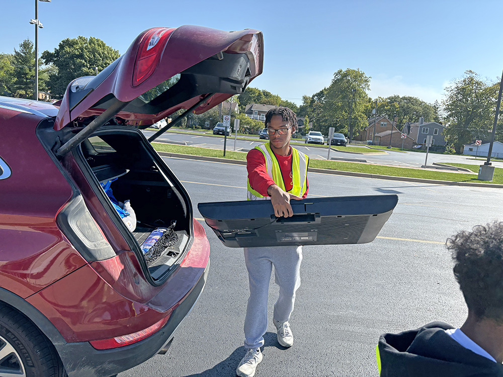 Isaiah Cole, a member of the Homewood-Flossmoor High Key Club, takes a TV for collection during Flossmoor's Recyclepalooza event Sept. 27. (Marilyn Thomas/H-F Chronicle)