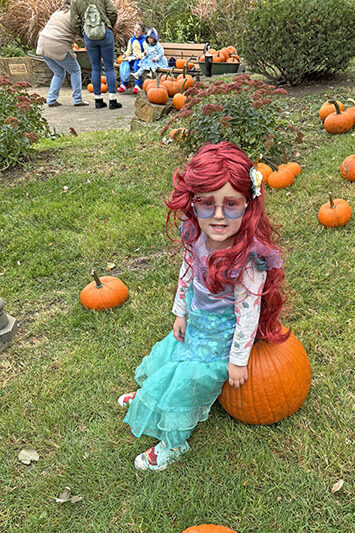 Little Mermaid Leila Kalvig took a break in the pumpkin patch sitting on her selection. (Marilyn Thomas/H-F Chronicle)