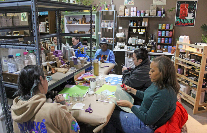 Attendees cut and layer thrifted paper for their decoupage jars during Gaia’s Crafting Workshop on Nov. 9 at Gaia’s Market & Refillery in Homewood. (Nuha Abdessalam/H-F Chronicle)