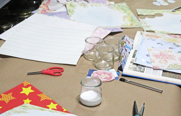 Sheets of patterned paper, jars, and glue covered the tables as attendees worked on upcycled projects. (Nuha Abdessalam/H-F Chronicle)