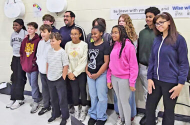 James Hart Orchestra pose for a photo with Homewood Arts Council Director Chris Castaneda, back center, after he announced the council received a grant that would pay for a field trip to a professional recording studio. (Eric Crump/H-F Chronicle)
