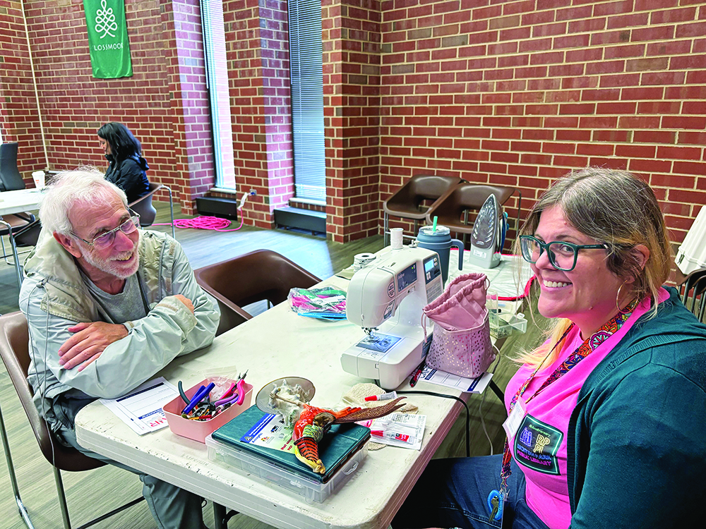 Scott Wolf and Laura Van Cleve chat while waiting for the glue to dry after Van Cleve was able to reattach a tail feather to Wolf's bird figurine. (Marilyn Thomas/H-F Chronicle)