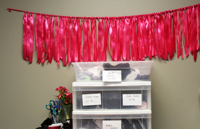 A line of ribbons hangs on the wall, each marking a pair of shoes given out through Sarah’s Soles. The board has been filling quickly since the program opened in February. (Nuha Abdessalam/H-F Chronicle)