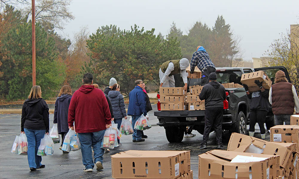 Volunteers carry Thanksgiving meal bags across the lot as distribution hits its morning peak during the annual Suburban Access Outreach Thanksgiving meal project. (Nuha Abdessalam/H-F Chronicle)