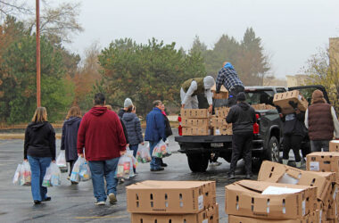 Volunteers carry Thanksgiving meal bags across the lot as distribution hits its morning peak during the annual Suburban Access Outreach Thanksgiving meal project. (Nuha Abdessalam/H-F Chronicle)
