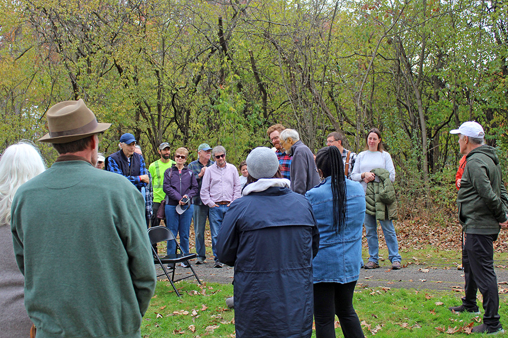 The community gathers to honor Tom Houlihan during a pawpaw planting event. Houlihan helped bring attention in Flossmoor to the native tree. (Nuha Abdessalam/H-F Chronicle)