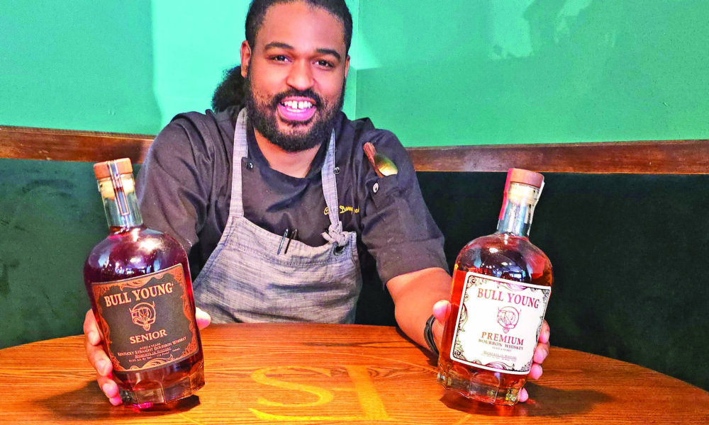Chef Danny Bullock with bottles of his own bourbon line. (Eric Crump/H-F Chronicle)