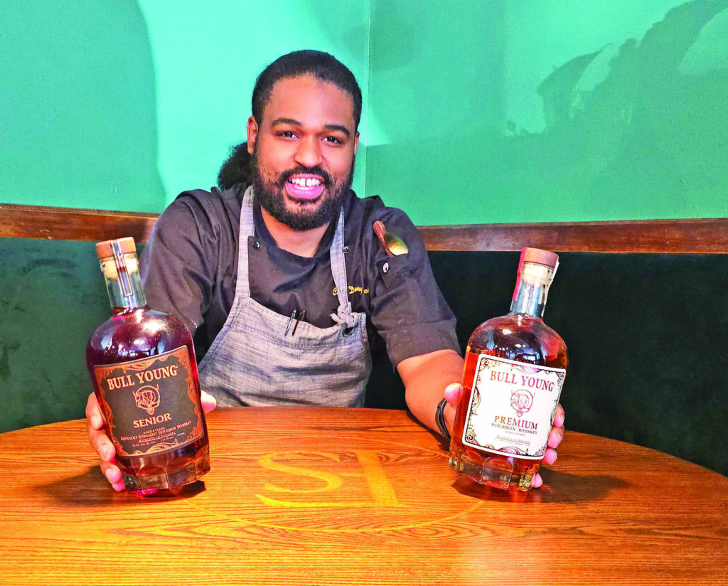 Chef Danny Bullock with bottles of his own bourbon line. (Eric Crump/H-F Chronicle)