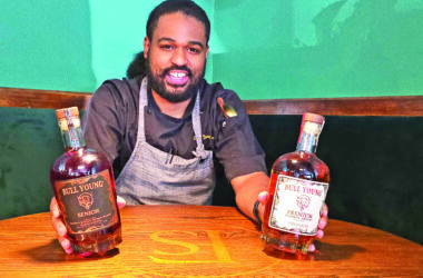 Chef Danny Bullock with bottles of his own bourbon line. (Eric Crump/H-F Chronicle)