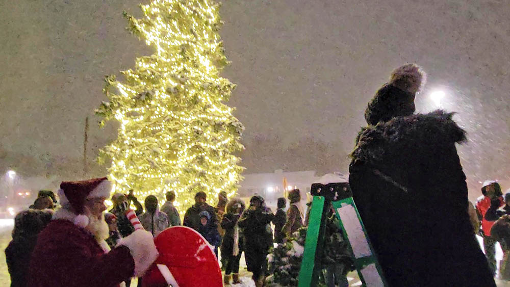 Santa pulls the lever to turn on the lights on the Flossmoor community Christmas tree at the village's holiday celebration on Nov. 29. (Eric Crump/H-F Chronicle)