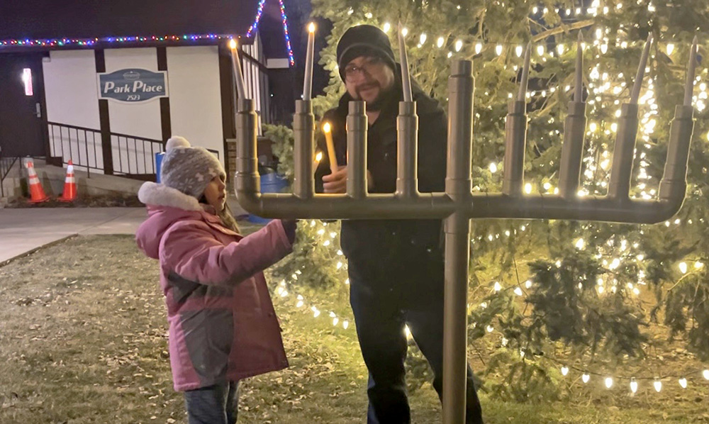 Jacob Schoeneman lights the Flossmoor menorah with help from his 7-year-old daughter, Holly Schoeneman, on Dec. 19, the sixth night of Hanukkah. (Nick Ulanowski / H-F Chronicle)(Nick Ulanowski / H-F Chronicle)