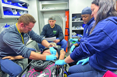 Paramedic-in-training Ryan Hope, left, attaches a lead to the model patient to get a heart reading. Working with him are Marquese Carter and Roisin Giblin. The instructor, in the top position, is Andrew Sline of the Homewood Fire Department. (Marilyn Thomas/H-F Chronicle)