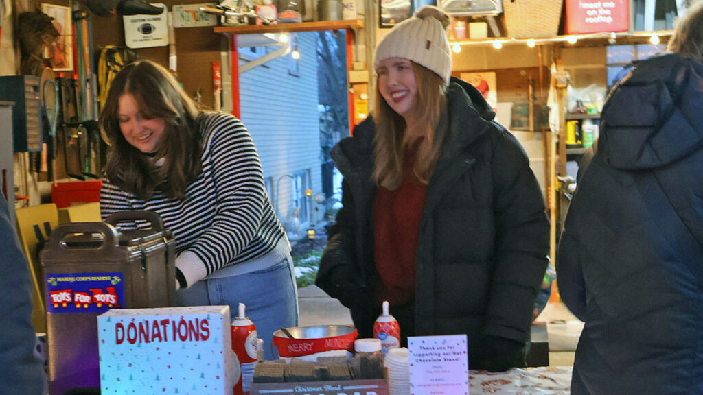 Kayla and Mara Winfrey serve hot chocolate at their 22nd annual stand, a tradition that has become a neighborhood staple. (Nuha Abdessalam/H-F Chronicle)