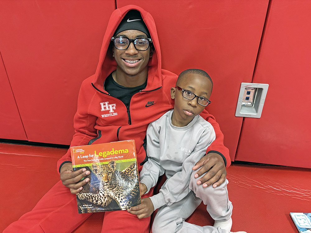 Ethan Dukes, a sophomore on the Homewood-Flossmoor High wrestling team, took time out from practice drills to read to his eight-year-old brother Ian as part of the teams Leaders Are Readers program. (Marilyn Thomas/H-F Chronicle)