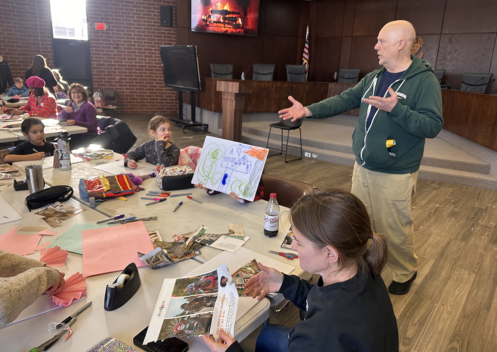 Flossmoor Public Art Commission member Jeff Stevenson draws attention to Simon Price, who shows off the yard sign he made. (Jon Bannister/H-F Chronicle)