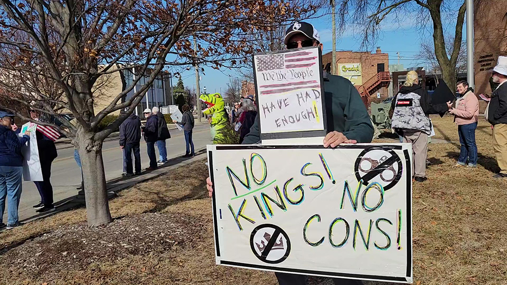 A demonstrator at the ABT Presidents Day rally in Homewood carries signs reading "We the people have had enough" and "No Kings! No Cons!" (Eric Crump/H-F Chronicle)