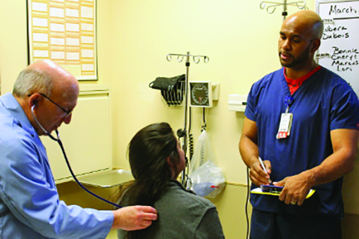 Dr. Bernard Heilicser, an urgent care physician, examines a patient at the Ingalls Family Care Center in Flossmoor in 2017. Assisting him is nurse Marcus Larrieu of Flossmoor. (Chronicle file photo)